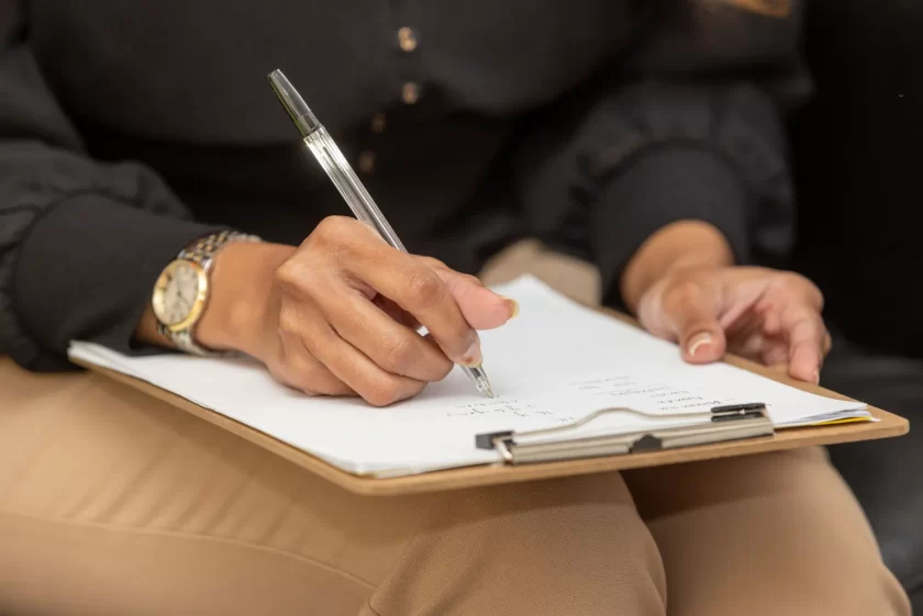 Person with clipboard balanced on knees