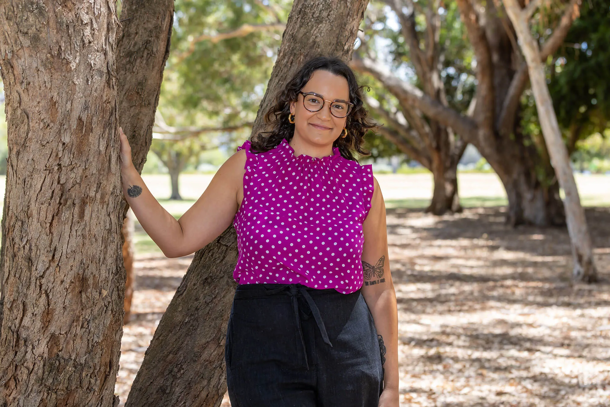 Young woman standing beside tree