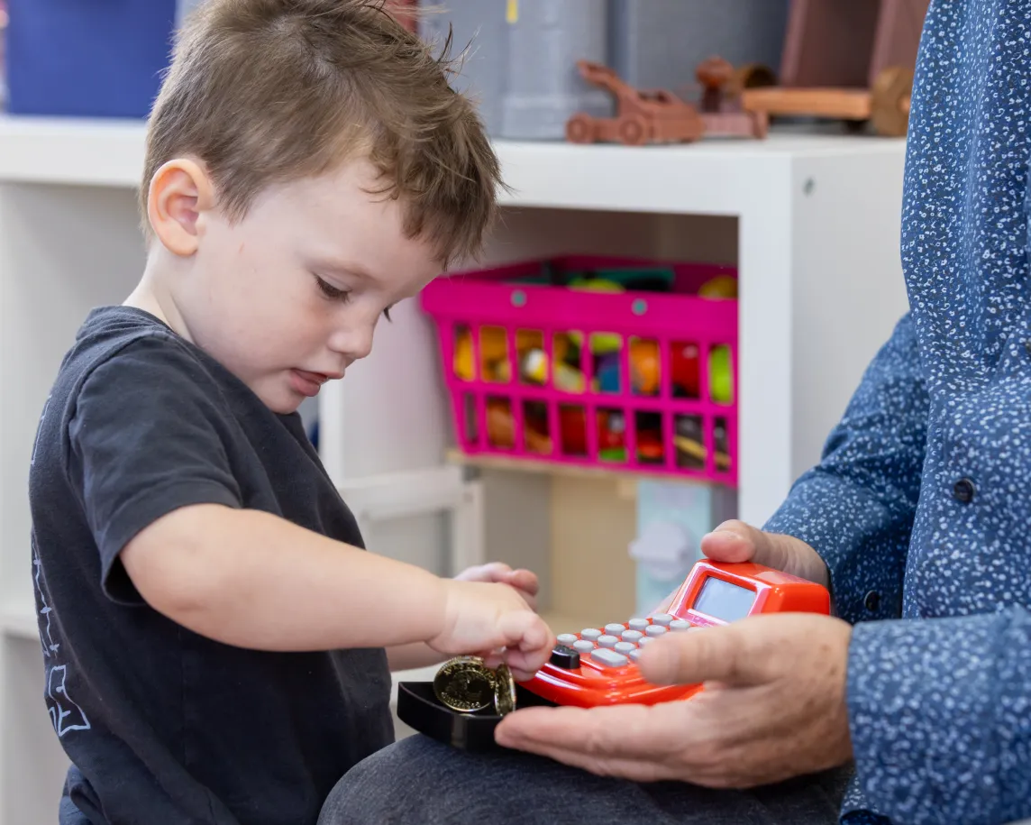 Boy putting coins in a cash register