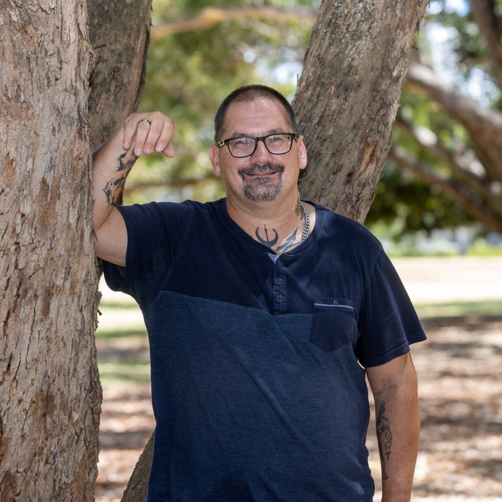 Happy man standing at tree after receiving free alcohol counselling from Holyoake in Perth, WA.
